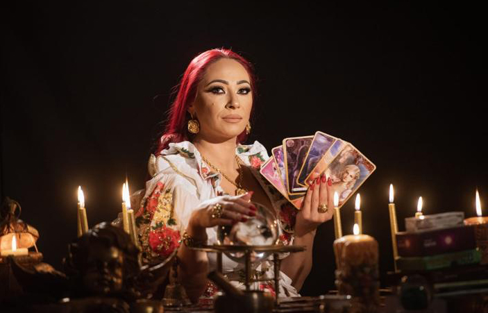 Danusia holding a fan of tarot cards by candlelight