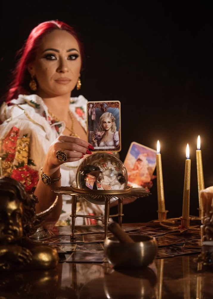 Danusia holding a tarot card above the crystal ball
